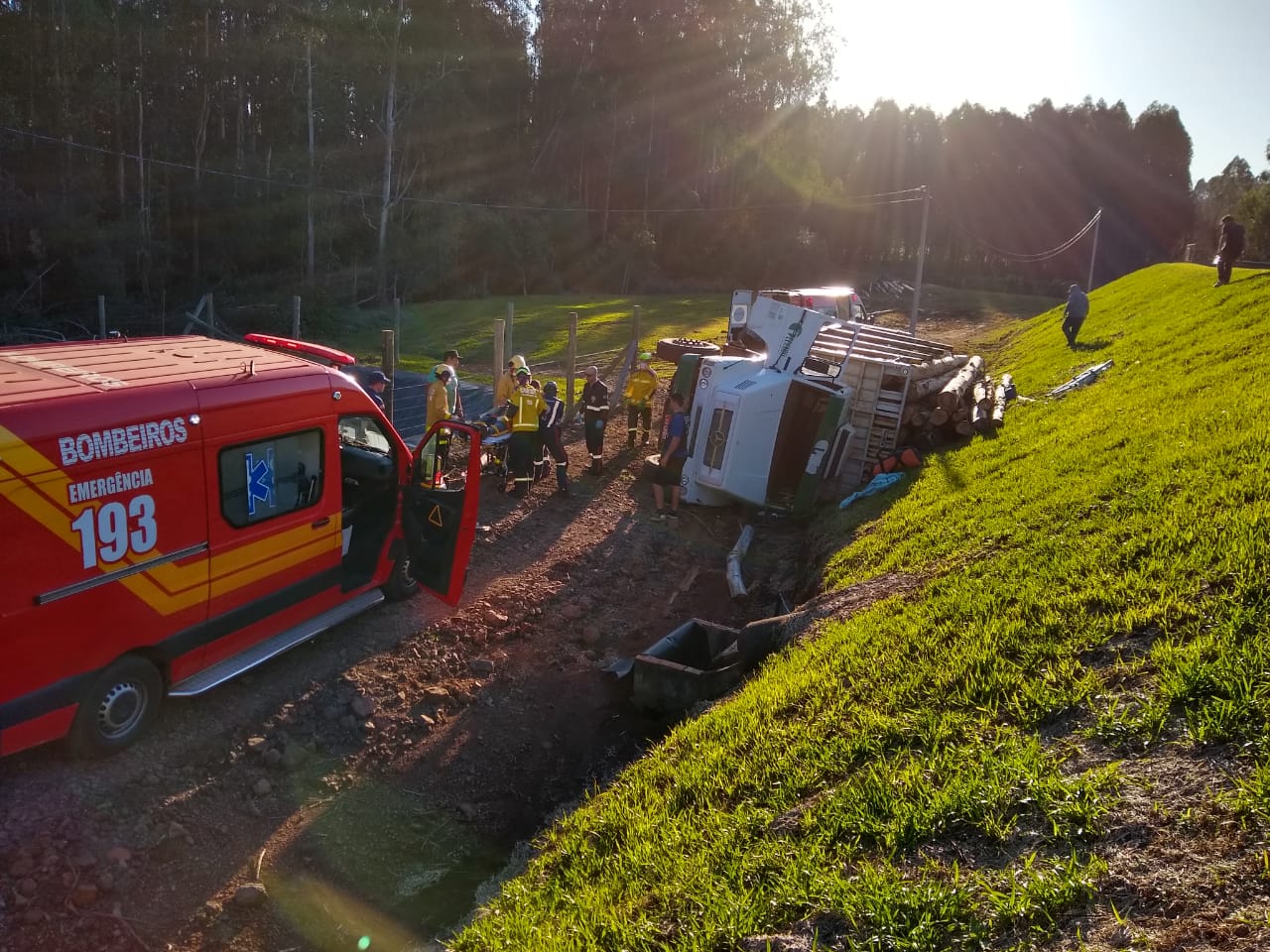 Caminhão carregado toras de madeira tomba e deixa motorista ferido